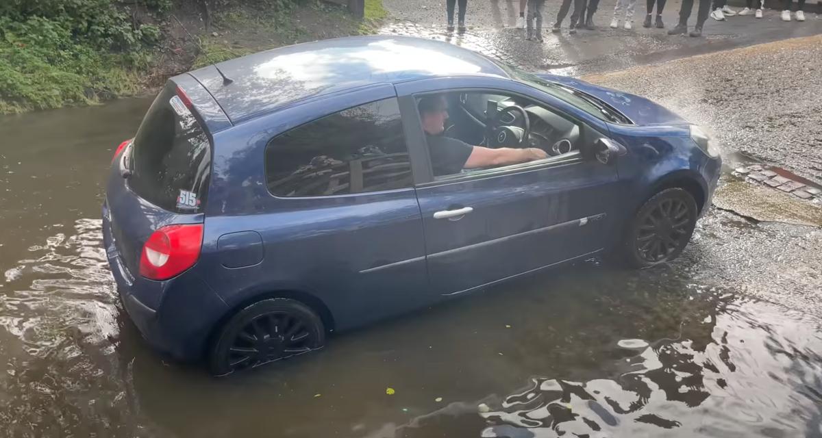Cette Clio tente de traverser une route inondée, son conducteur doit compter sur un remorquage pour s'en tirer